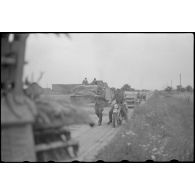 Un équipage de Sturmhaubitze 42 (StuH 42) se mêle avec des fantassins, le blindé est peut-être endommagé.