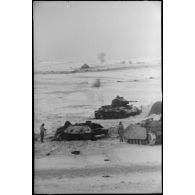 Un équipage d'un canon d'assaut examine deux carcasses de chars soviétiques T-34.