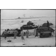 Un équipage d'un canon d'assaut examine deux carcasses de chars soviétiques T-34.