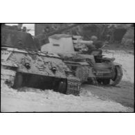 Un Sd.kfz.124 "Wespe" passe devant un char soviétique T-34 détruit.