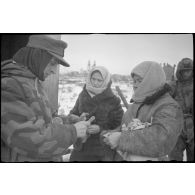 Un soldat effectue un contrôle des papiers d'identité de deux passantes.