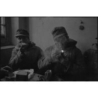 Des fantassins terminent un repas à l'abri d'une maison.