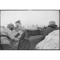 Tireur et pourvoyeur derrière une mitrailleuse MG-34 en pleine action.