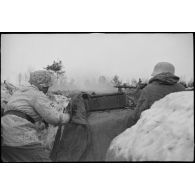 Tireur et pourvoyeur derrière une mitrailleuse MG-34 en pleine action.