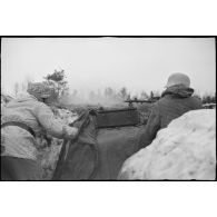 Tireur et pourvoyeur derrière une mitrailleuse MG-34 en pleine action.