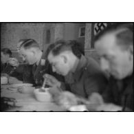 Le général (Generalleutnant) Robert Pistorius partage un repas avec des hommes 4e division d'infanterie de l'armée de l'air allemande après avoir prononcé un discours.