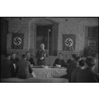 Le général (Generalleutnant) Robert Pistorius partage un repas avec des hommes 4e division d'infanterie de l'armée de l'air allemande après avoir prononcé un discours.