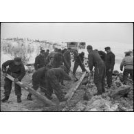 Pris dans la glace, les rondins qui consolidaient la route sont détruits à l'aide d'explosifs.
