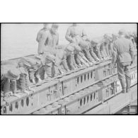 Déploiement de poutres métalliques du ponton (Brückegerät) pour faire descendre ou monter un véhicule.