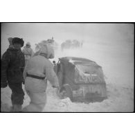 Une Kübelwagen immatriculée WH-1432 613 tente de reprendre la route, des semi-chenillés attentent de passer le pont.