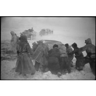 Une Kübelwagen immatriculée WH-1432 613 tente de reprendre la route, des semi-chenillés attentent de passer le pont.