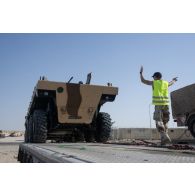 Un soldat du 5e régiment de cuirassiers (RC) guide le chargement d'un véhicule blindé de combat d'infanterie (VBCI) à bord d'un porte-engins blindé (PEB) émirien à Zayeb military city, aux Emirats arabes unis.