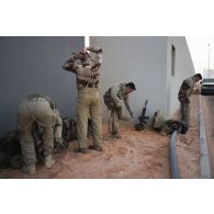Des soldats du 92e régiment d'infanterie (RI) enfilent leur tenue de protection à port permanent (T3P) pour une progression en milieu contaminé sur le camp d'Al Hamra, aux Emirats arabes unis.