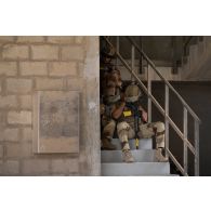 Un groupe de combat du 92e régiment d'infanterie (RI) se repose à l'abri d'un bâtiment à la tombée de la nuit sur le camp d'Al Hamra, aux Emirats arabes unis.