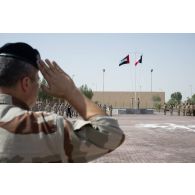 Un officier du 5e régiment de cuirassiers (RC) salue le lever des couleurs sur la place d'armes de Zayed military city, aux Emirats arabes unis.