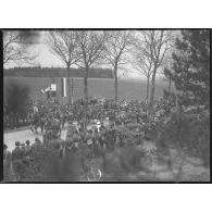 Sur une route, les troupes polonaises (75 mm M1897 hippomobile) défilent devant les officiels civils et militaires, polonais et français.
