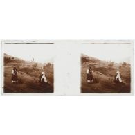 [Vie locale : deux  personnes avec des fagots de bois au bord d'une route].