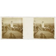 [Vie locale : groupe de femmes sur la place d'un village, ombre du photographe au premier plan].<br>