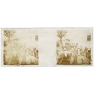 [Vie locale : groupe de femmes sur la place d'un village, ombre du photographe au premier plan].<br>