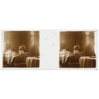 [Hôpital militaire de Verdun : blessé alité et blessé debout dans une chambre, avec table ronde au premier plan].