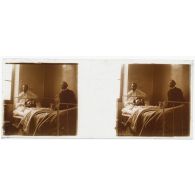 [Hôpital militaire de Verdun : blessé alité et blessé debout dans une chambre ; homme vêtu de noir à droite].