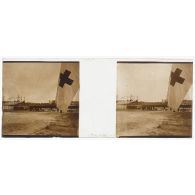 [Cérémonie militaire à Longchamp ? : vue générale avec drapeau à croix rouge au premier plan].<br>