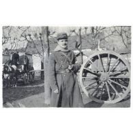 [Un soldat du service de santé (infirmier ?) se tient la pipe à la main devant une charrette].