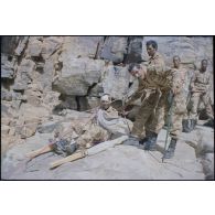 Formation des aides moniteurs commando et des élèves officiers de l'école militaire interarmes d'Atar à l'escalade et au rappel, aux techniques de cordes et d'assurance, au franchissement de fortune, au brancardage dans les falaises de l'Oued Illïj, région d'Atar et d'Azougui. Température d'exercice avoisisant les 40° en raison du rayonnement sur les parois rocheuses, 300 élèves et 10 aides moniteurs ont été formés pendant cette période. [légende d'origine]<br>