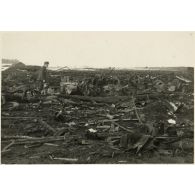 [Un soldat constate les dégâts causés par un bombardement, au centre un side-car].