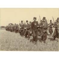 La marche en colonne par quatre. Il fait chaud. Le soleil tape sur les nuques. Très débraillés, les képis en bataille, les pioupous chantent, l'air très crâne.
