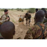 Les résultats du tir sur la cible sont commentés par l'officier de tir français en présence des stagiaires tireurs maliens.