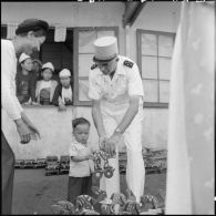 Distribution de jouets et de friandises par le général de Linarès et une assistante sociale aux enfants réfugiés Muong de Kobe à l'occasion des fêtes de la mi-automne.