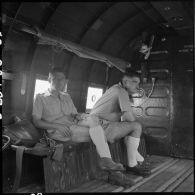 A bord d'un avion de transport Douglas C-47, deux militaires accompagnant le général Cogny, commandant des FTVN (Forces terrestres du Nord-Vietnam), lors d'une visite du camp retranché de Na San en cours d'évacuation.
