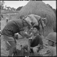 Un rebelle est soigné par le médecin-lieutenant Duc, médecin du 3e BPVN (bataillon de parachutistes vietnamiens), après la prise du village de My Ngo lors de l'opération Flandres.