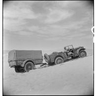 Un tracteur Latil franchit une dune attelé à une remorque.