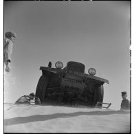 Plan en contre-plongée de l'avant d'un tracteur Latil qui franchit une dune à l'aide d'échelles droites, système d'aide au passage.