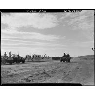 Une autorité militaire passe en revue des troupes, à bord d'un véhicule blindé.