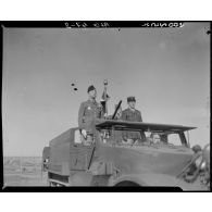 Plan rapproché du général de division André Kientz, qui passe en revue des troupes, à bord d'un véhicule blindé.