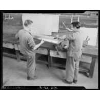 Deux élèves de l'Ecole de l'Air de Cap Matifou, s'exercent à travailler sur une pièce d'avion, dans un atelier.