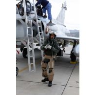 Au retour de mission, un pilote qatari à la descente de son avion Mirage 2000-5 QA 85, tandis que le mécanicien de piste accueille l'autre membre de l'équipage au cockpit.
