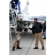 Au retour de mission, un pilote qatari salue un collègue à la descente de son avion Mirage 2000-5 QA 85, tandis que le mécanicien de piste accueille l'autre membre de l'équipage au cockpit.