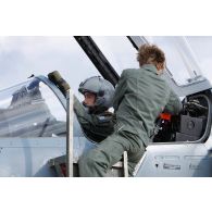 Au départ en mission, le sergent féminin mécanicien de piste vecteur de l'ESTA (escadron de soutien technique aéronautique) 2E Chalosse de la BA 118 assiste le pilote d'un avion Mirage 2000-5 de l'EC (escadron de chasse) 1/2 Cigognes installé dans le cockpit.