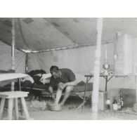 [Un militaire se lave les pieds sous une tente].