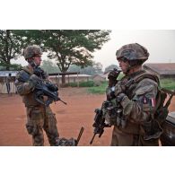 Deux militaires de la section QRF du SGTIA Gris du GTIA Picardie se déploient sur un axe longeant le camp Béal, où sont regroupés des ex-Seleka. Ils font un compte-rendu radio.