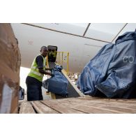 Les colis sont déchargés de l'avion-cargo Boeing 777F d'Air-France KLM par le personnel de l'aéroport de Bangui M'Poko, utilisant un engin convoyeur élévateur Tug.