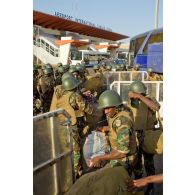 Des militaires togolais chargent leurs paquetages dans la soute d'un bus avant embarquement devant l'aérogare de l'aéroport de Bamako.