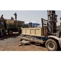 Opération de chargement de caisses de munitions sur un camion à l'aide d'un engin de manutention transpalettes par des militaires maliens. En arrière-plan, un avion de transport Boeing 747-400 ERF de la compagnie ABC (Airbridge Cargo) sur la piste de l'aéroport.