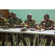 Dans une salle de formation, des stagiaires du Bénin et du Sénégal, disposant d'un manuel d'instruction (édité par l'état-major des Armées de la république du Mali et le CICR (comité international de la Croix-Rouge)), écoutent le cours.