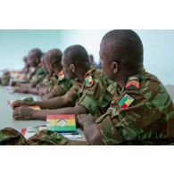Dans une salle de formation, des stagiaires béninois, disposant d'un manuel d'instruction (édité par l'état-major des Armées de la république du Mali et le CICR (comité international de la Croix-Rouge)), écoutent le cours.