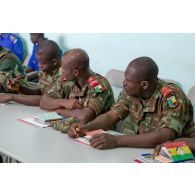 Dans une salle de formation, des stagiaires béninois, disposant d'un manuel d'instruction (édité par l'état-major des Armées de la république du Mali et le CICR (comité international de la Croix-Rouge)), écoutent le cours.